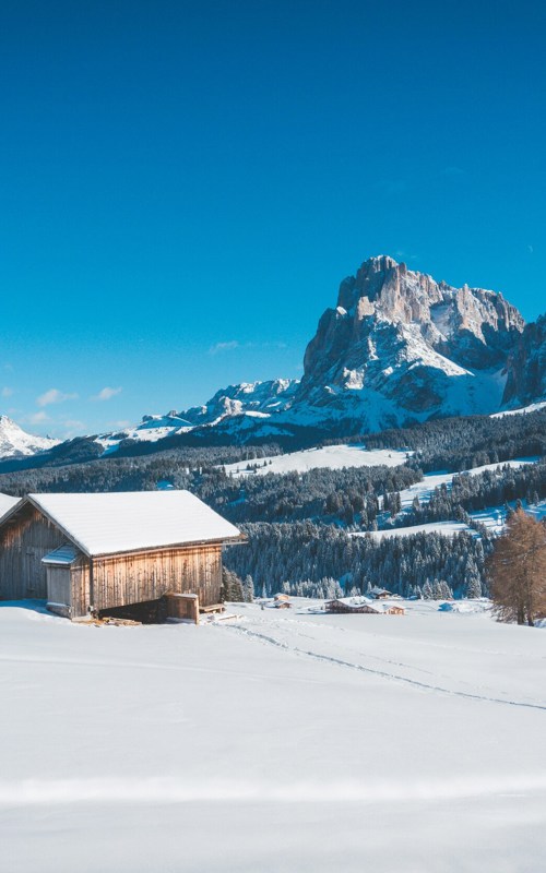Mountain hut on the Alpe di Siusi in winter Winter landscape and dolomites against a blue sky
